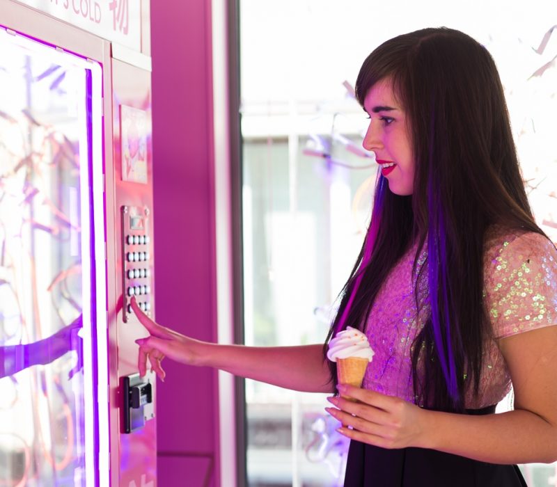 Pretty young woman using a modern beverage vending machine.